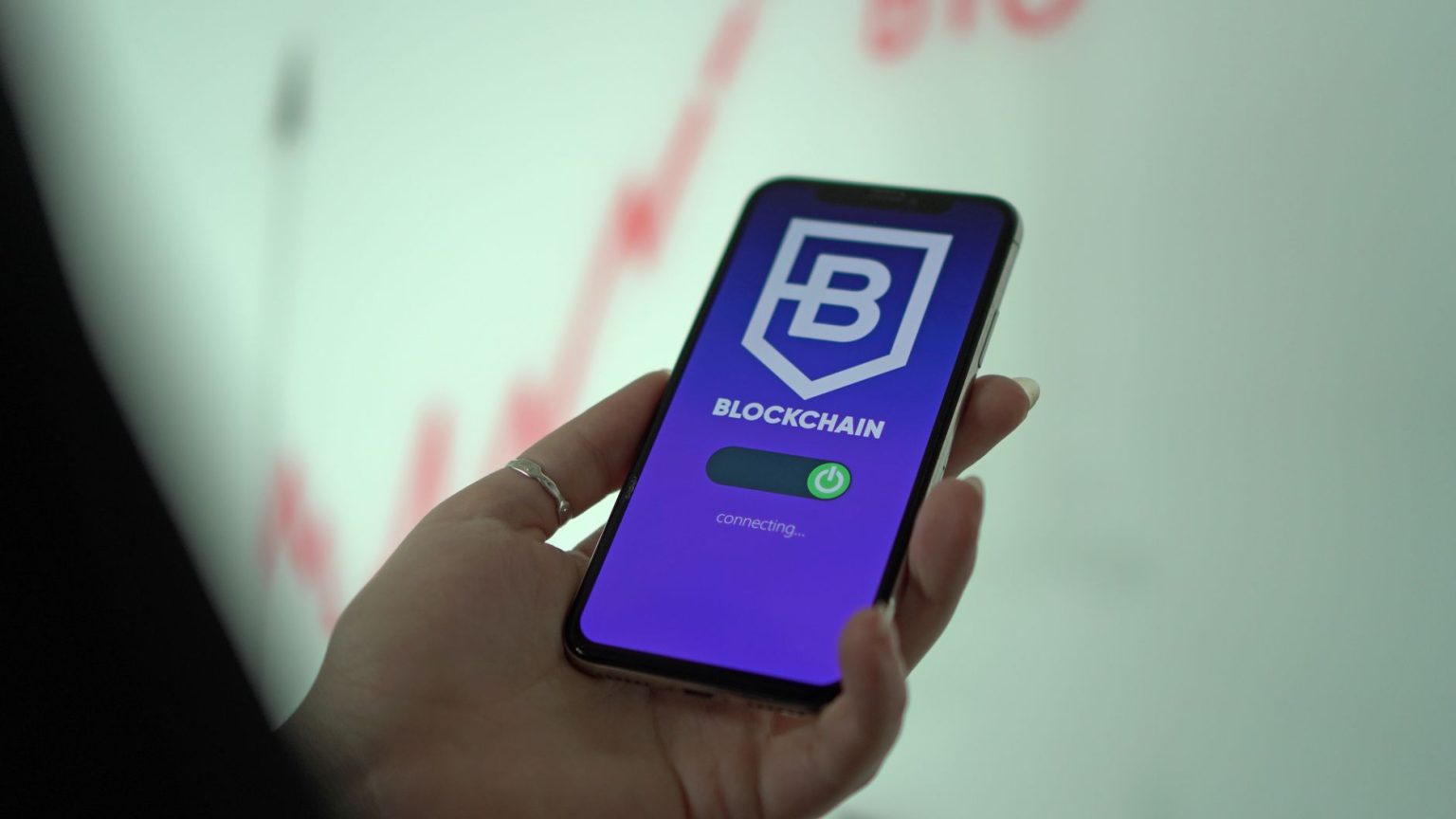 Pessoa segura um smartphone que exibe uma carteira digital de criptomoedas baseada em blockchain.