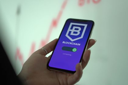 Pessoa segura um smartphone que exibe uma carteira digital de criptomoedas baseada em blockchain.