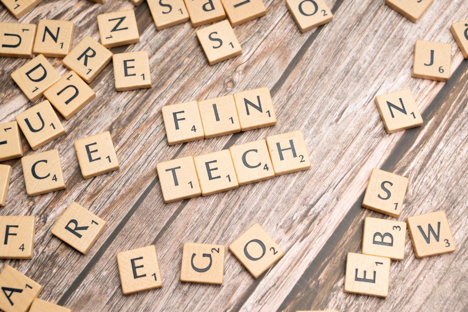 A palavra fintech formada por letras de madeira sobre uma superfície de madeira.
