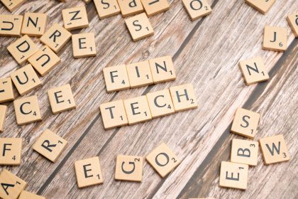 A palavra fintech formada por letras de madeira sobre uma superfície de madeira.