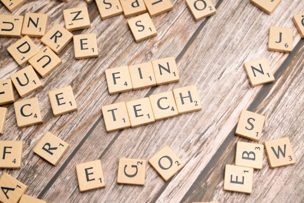A palavra fintech formada por letras de madeira sobre uma superfície de madeira.