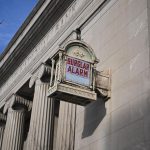 Edifício bancário histórico de estilo neoclássico nos Estados Unidos, com fachada clara e placa de alarme.