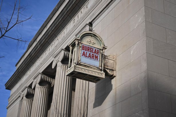 Edifício bancário histórico de estilo neoclássico nos Estados Unidos, com fachada clara e placa de alarme.