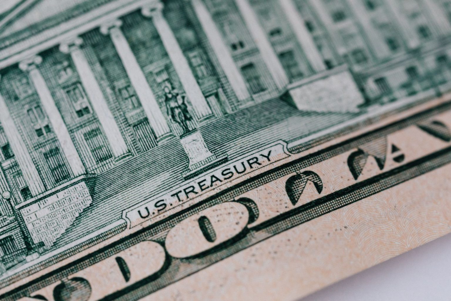 Cédula de dez dólares e edifício do Tesouro dos Estados Unidos sobre uma mesa.