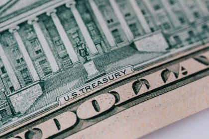 Cédula de dez dólares e edifício do Tesouro dos Estados Unidos sobre uma mesa.
